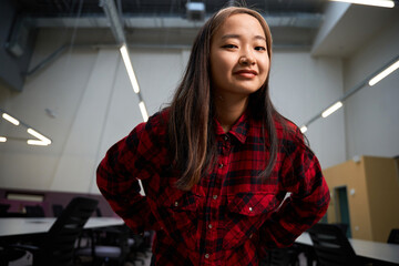 Bottom view of asian female IT employee winking at camera in coworking office