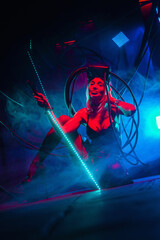 Beautiful futuristic girl posing with light sword katana in the neon lights. Cyberpunk concept.