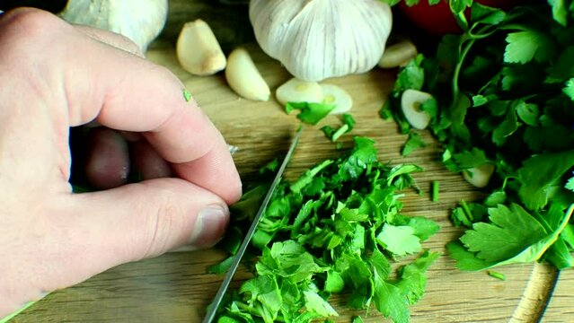 Chef mincing parsley greens on wooden board	