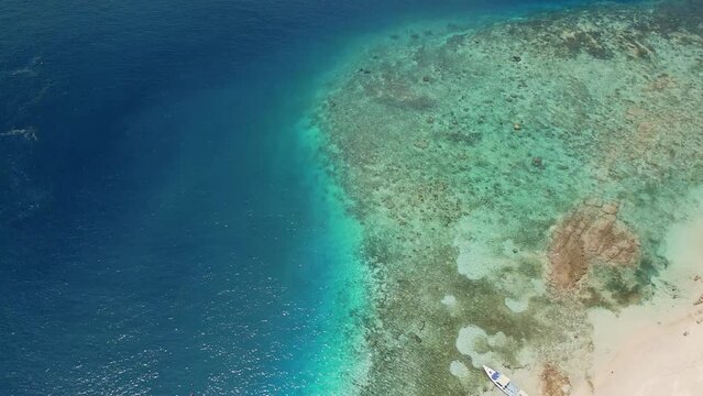 Top down aerial view of tourist boats on the edge of a fringing coral reef on a tropical island