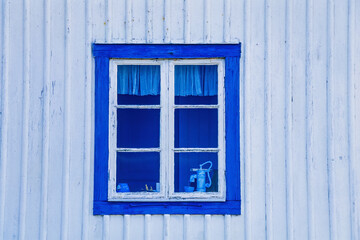 Blue window on white wooden cottage