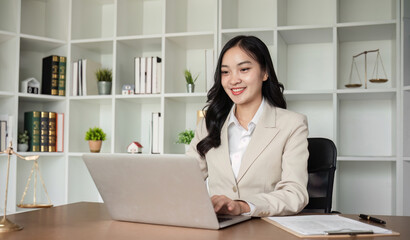 A female Asian lawyer reviews business and real estate laws. Legal consultants provide legal advice and guidance online via laptops in lawyers' offices.