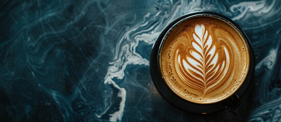 A cup of latte with art on a marbled surface.