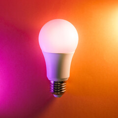 Light bulb on colorful pastel background. Smart home device.