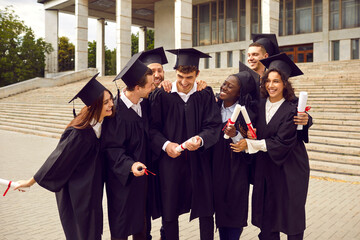 Group of a smiling happy multiracial international graduates students hugging and having fun in a...