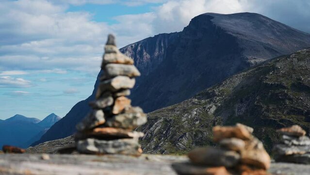 Stone cairns are arranged on the rocks. Dark mountains tower in the background. Slow-motion, parallax shot.