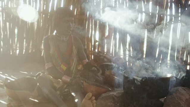 Hamer tribe Mother and daughter in a hut making food