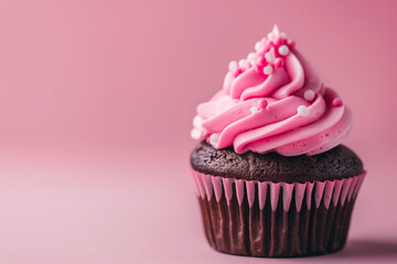 A delightful chocolate cupcake with pink frosting and sprinkles rests on a pink background - obrazy, fototapety, plakaty
