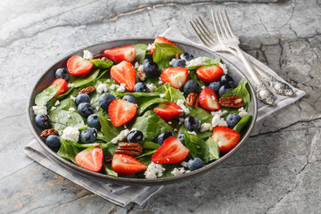 Healthy Spinach salad with berries such as strawberries, blueberries with cheese and pecans and...