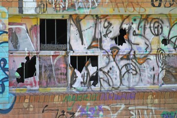 Urban decay - old factory windows with graffitti and broken windows