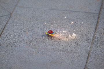 A sparkling firecracker spins on the road tiles