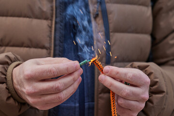 Close up of man hand lighting up a firecrackers with wick