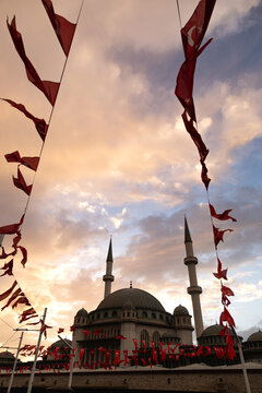 Taksim Camii mosque and turkish flags under a sunset sky