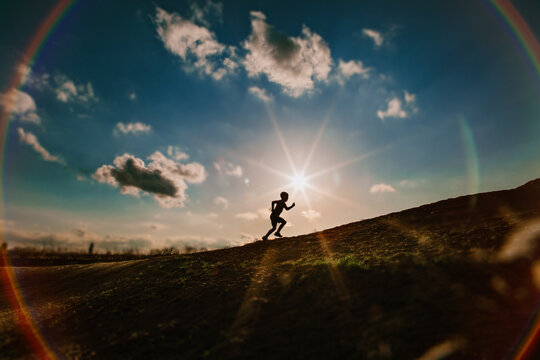 Boy Running Uphill with blue sky and clouds