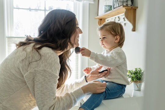 Toddler Girl Helping Mother Put on Make Up