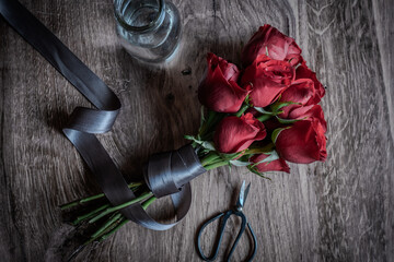 Overhead shot of blooming red roses wrapped in gray ribbon.