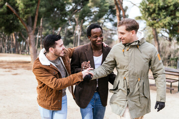 three multiracial friends walking down around trees