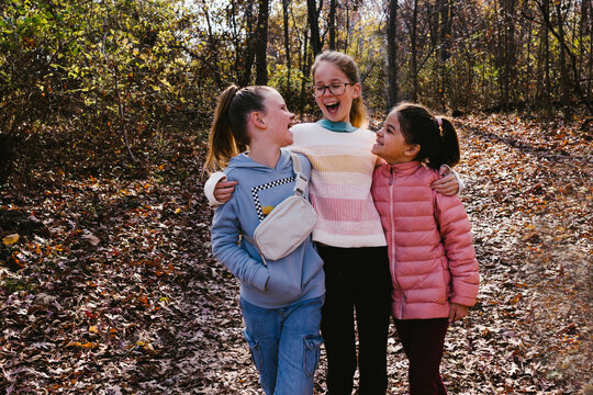 Girls laugh and talk of multi race in fall leaves in forest