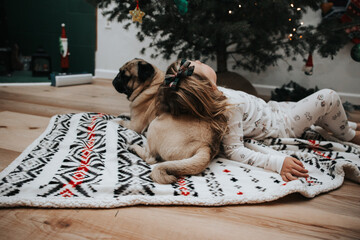 Cute girl in Christmas pajamas with pug pillow