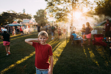 Child smiling at summer carnival during golden hour