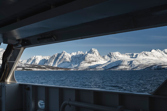 Fototapeta Scenic view of snowcapped mountains by sea seen through window of boat