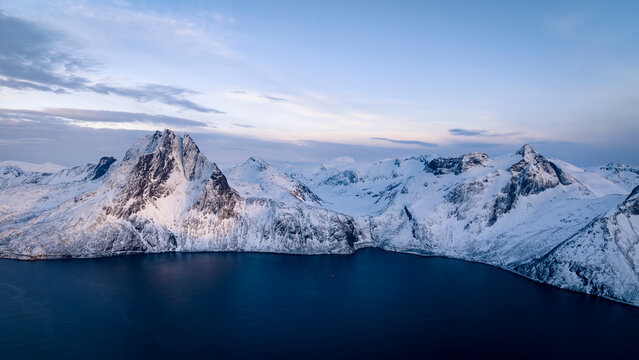 Drone Shot Of Snowcapped Mountains In Front Of Sea Against Sky At Dusk