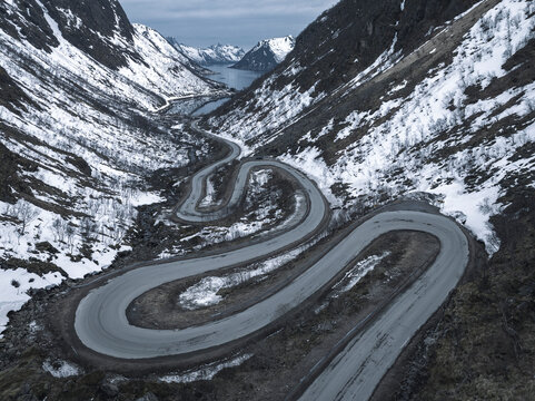 Drone shot of winding road on snow covered mountains