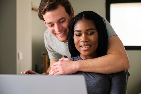 Multiracial happy couple using the laptop to make a reservation.