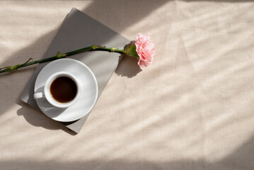 Minimalist aesthetic spring or summer still life, coffee cup, notebook and carnation flower on...