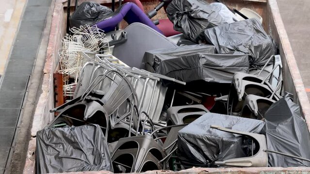 Plastic waste above a conveyor belt inside a recycling center furniture chairs 