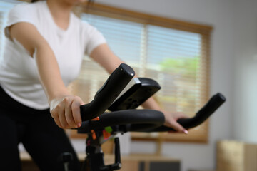 Fototapeta na wymiar Cropped shot of young woman doing cardio on stationary bike at home