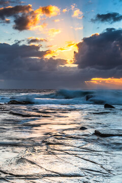 Moody sunrise seascape with clouds and sunrays at the rocky inlet
