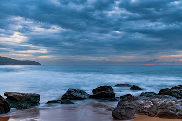Sunrise at the seaside with rocks and beautiful diffused light by the rain clouds