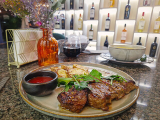 Grilled beef steak on the table in a fancy restaurant with a view to the wine shelves on the...