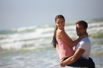 Fototapeta premium Sea, couple and man lifting woman, travel and freedom at beach for bonding and anniversary date in nature. Happy, partner and commitment with view, affection and playful outdoor for love and fun