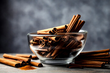 Ceylon cinnamon sticks in glass plate on wooden board at grey textured wall, rustic style. Still life natural food of cinnamon sticks on wood table. Delicious tasty healthy concept. Copy ad text space - obrazy, fototapety, plakaty