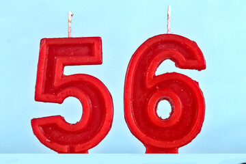 close up on red number fifty fifth birthday candle on a white background.
