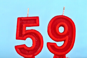 close up on red number fifty ninth birthday candle on a white background.
