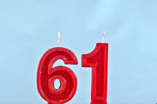 close up on red number sixty one birthday candle on a white background.
