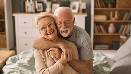 Embraced senior couple smiling and relaxing in bed