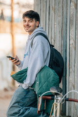 young man on street wall with mobile phone and vintage bicycle with copy-space