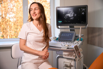 Female doctor at ultrasound scanning equipment in gynecological cabinet