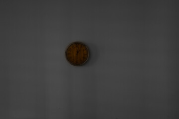 A minimalist modern wooden clock with numbers, made of concrete, hanging on white wall in the rays...