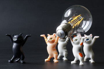 Funny toy kittens carry a modern energy-saving LED lamp in their paws. An educational concept for saving electricity. Electrification. Toy world. Photo