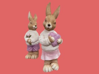 two stone figurines of bunnies with flowers and a heart on a pink background