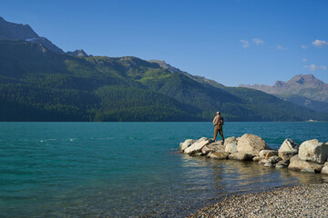 Fisherman with fishing rod on the shore. Blue lake in the mountains. Recreational area for...