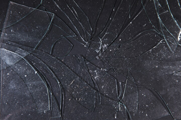 Shattered glass fragments scatter upon shadowed ground, an intricate texture overlaying the dark...