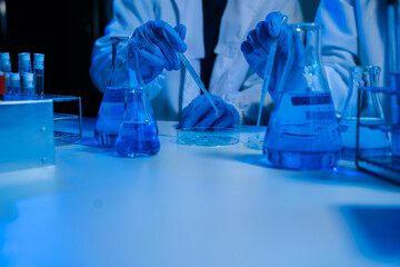 Science and medicine, scientist analyzing and dropping a sample into a glassware, experiments containing chemical liquid in laboratory on glassware, innovative and technology.