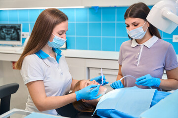 Assistant helps dentist at a reception, she holds saliva ejector
