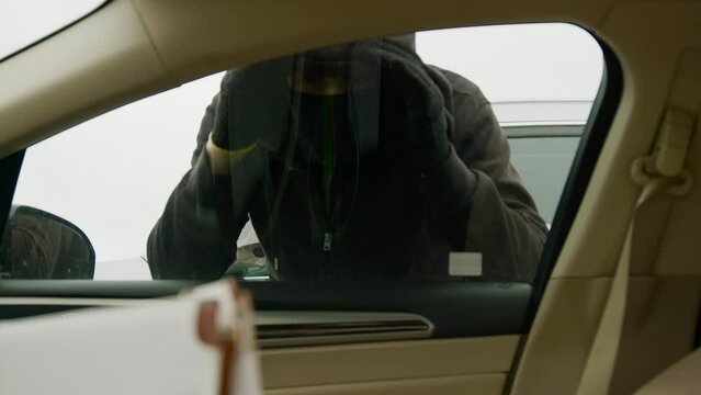 Car thief burglar looking through window contemplating his illicit entry. Looking through window car thief burglar evaluates interior searching for valuables Looking through window car thief burglar.